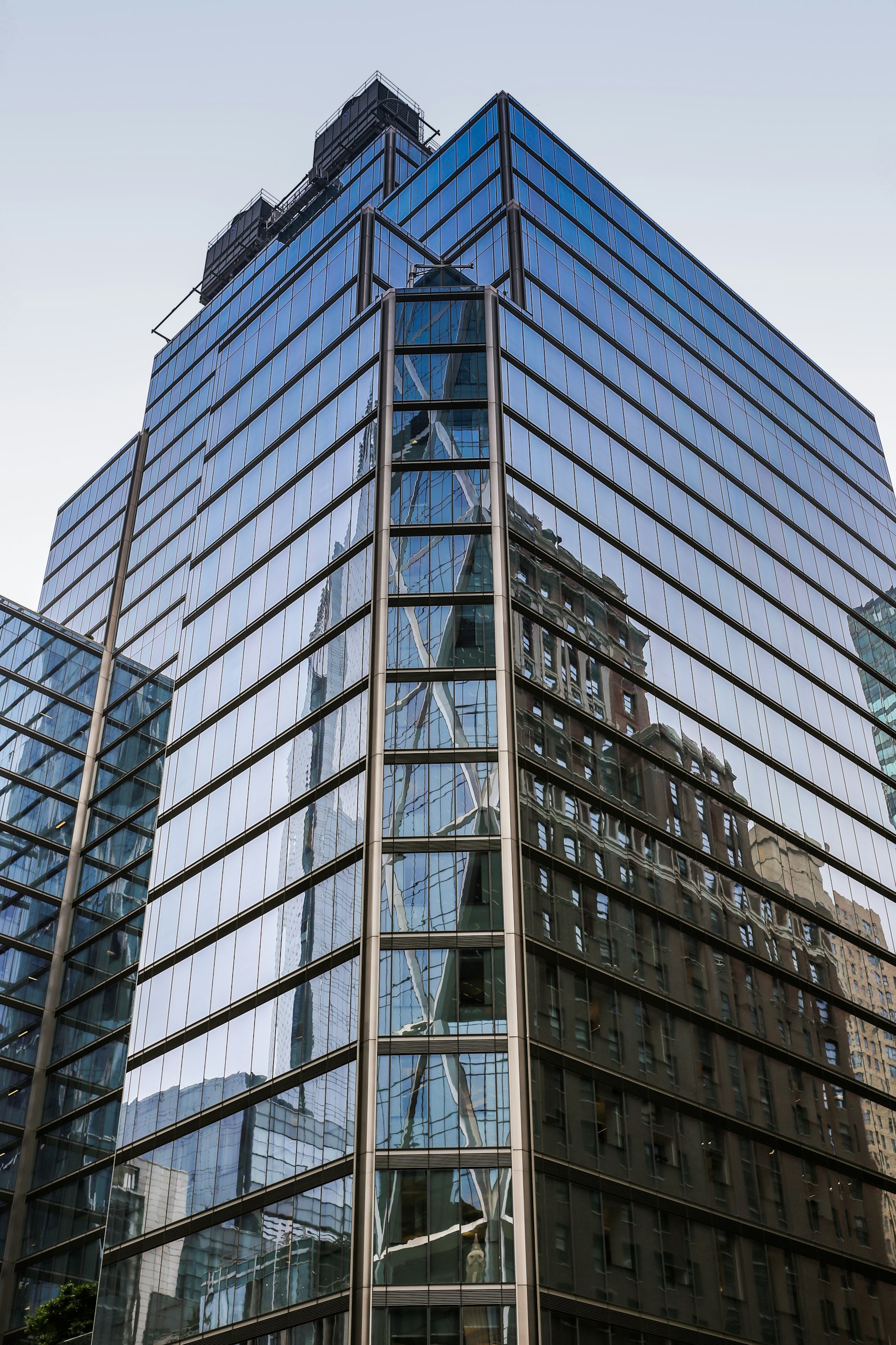 Modern glass commercial office building reflecting clouds and sky