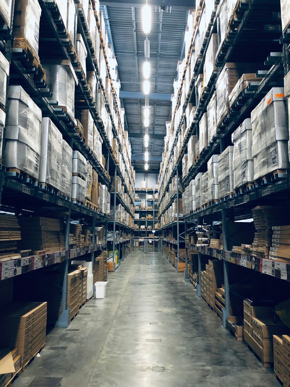 Organised warehouse with tall pallet racks and a clear central aisle